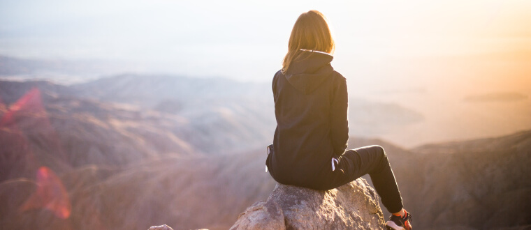 A woman at the top of the mountain admiring the view