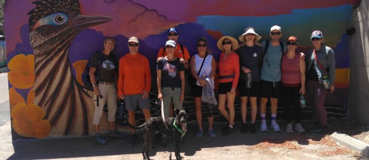 A group of friends with their dog in front of colorful Bisbee street art