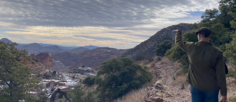 Male guide pointing out Bisbee viewpoints on hike around Bisbee